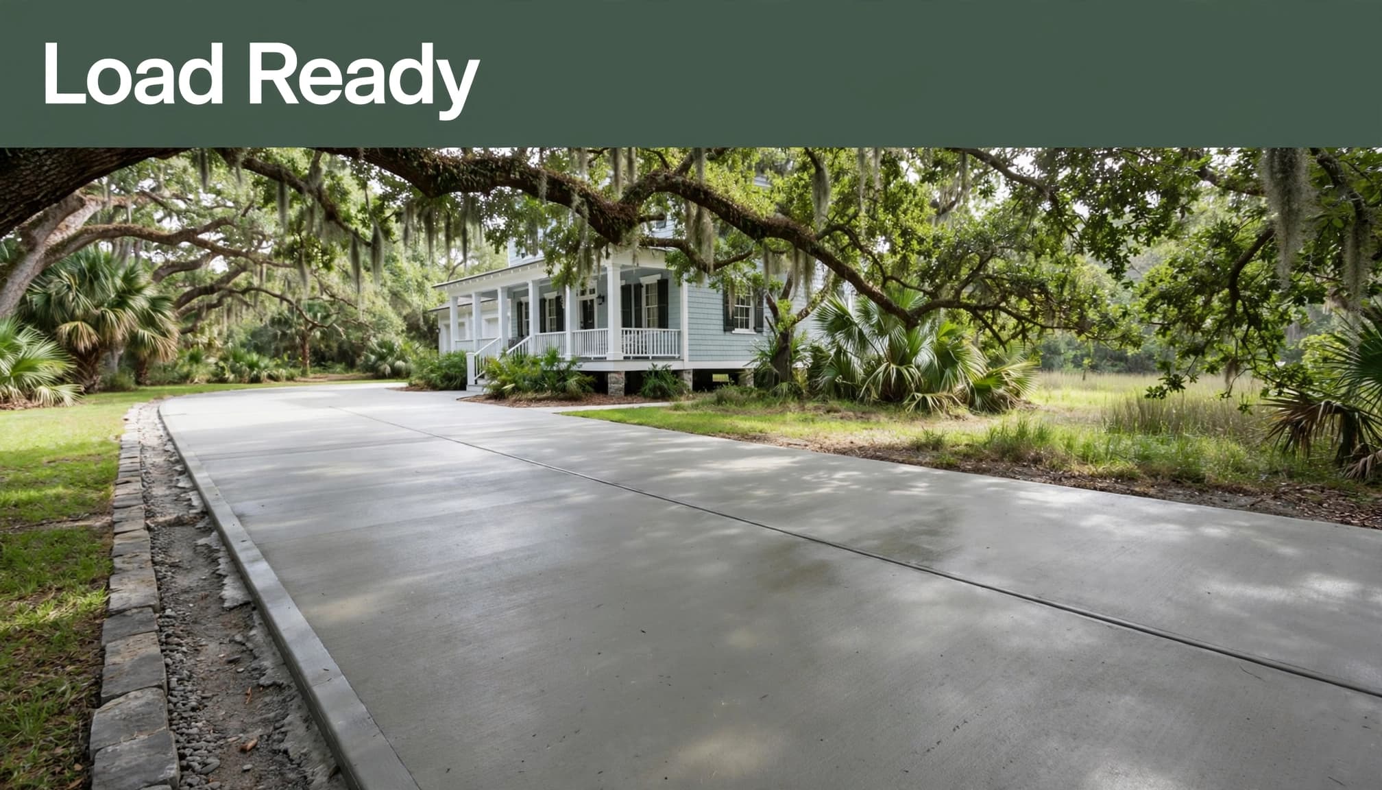 Fresh concrete driveway with a control joint and exposed stone edge.